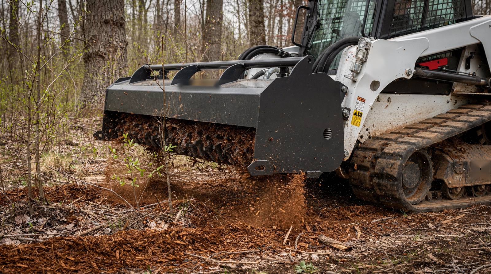 Forestry mulching head on a compact track loader grinding brush and saplings into mulch